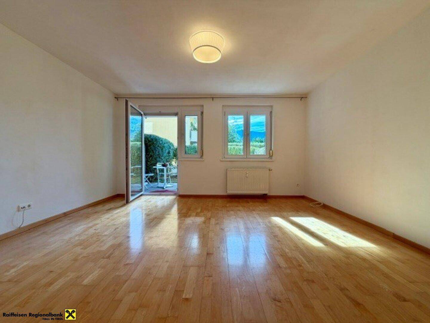 Heller Wohnraum mit Parkettboden und Zugang zu einer Terrasse, durchflutet von natürlichem Licht.