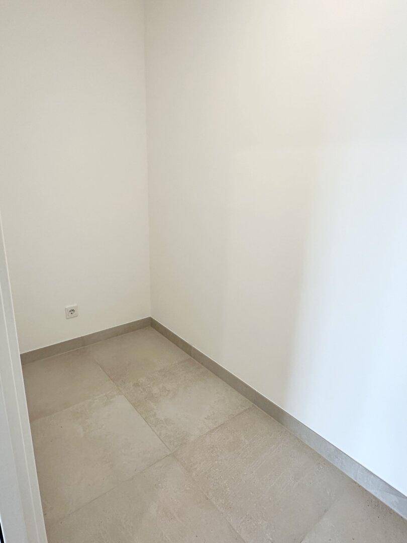 Kleiner, sauberer Abstellraum mit Fliesenboden und weißen Wänden, ideal für zusätzlichen Stauraum.