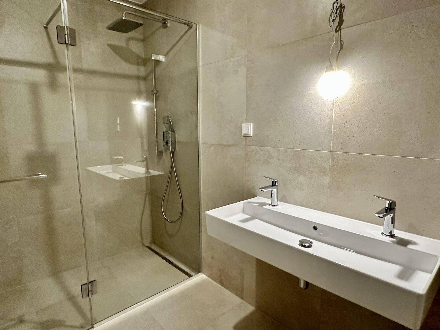 Modernes Badezimmer mit begehbarer Dusche, Regendusche und Doppelwaschbecken, hell gefliest.