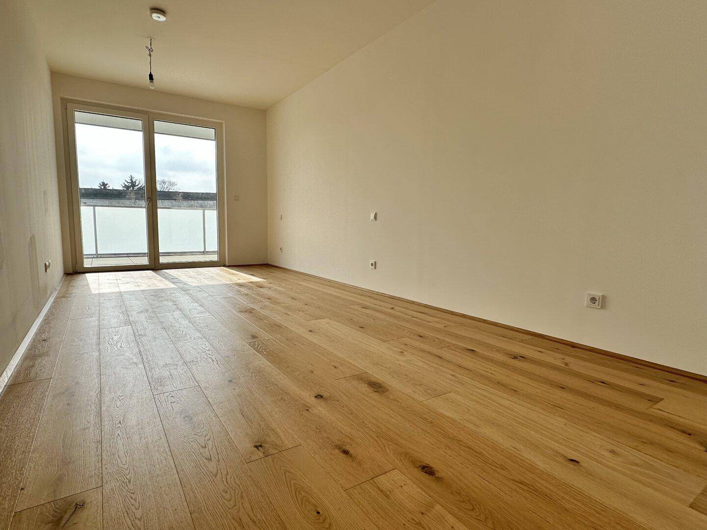 Geräumiges Zimmer mit Eichenparkett und Zugang zu einem Balkon oder einer Terrasse.
