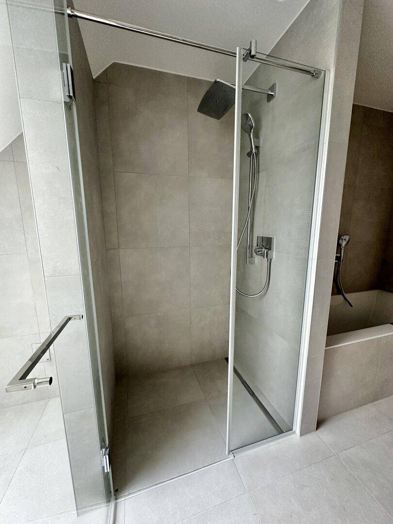 Moderne begehbare Dusche mit Glasabtrennung und Regenduschkopf in einem stilvollen Badezimmer.