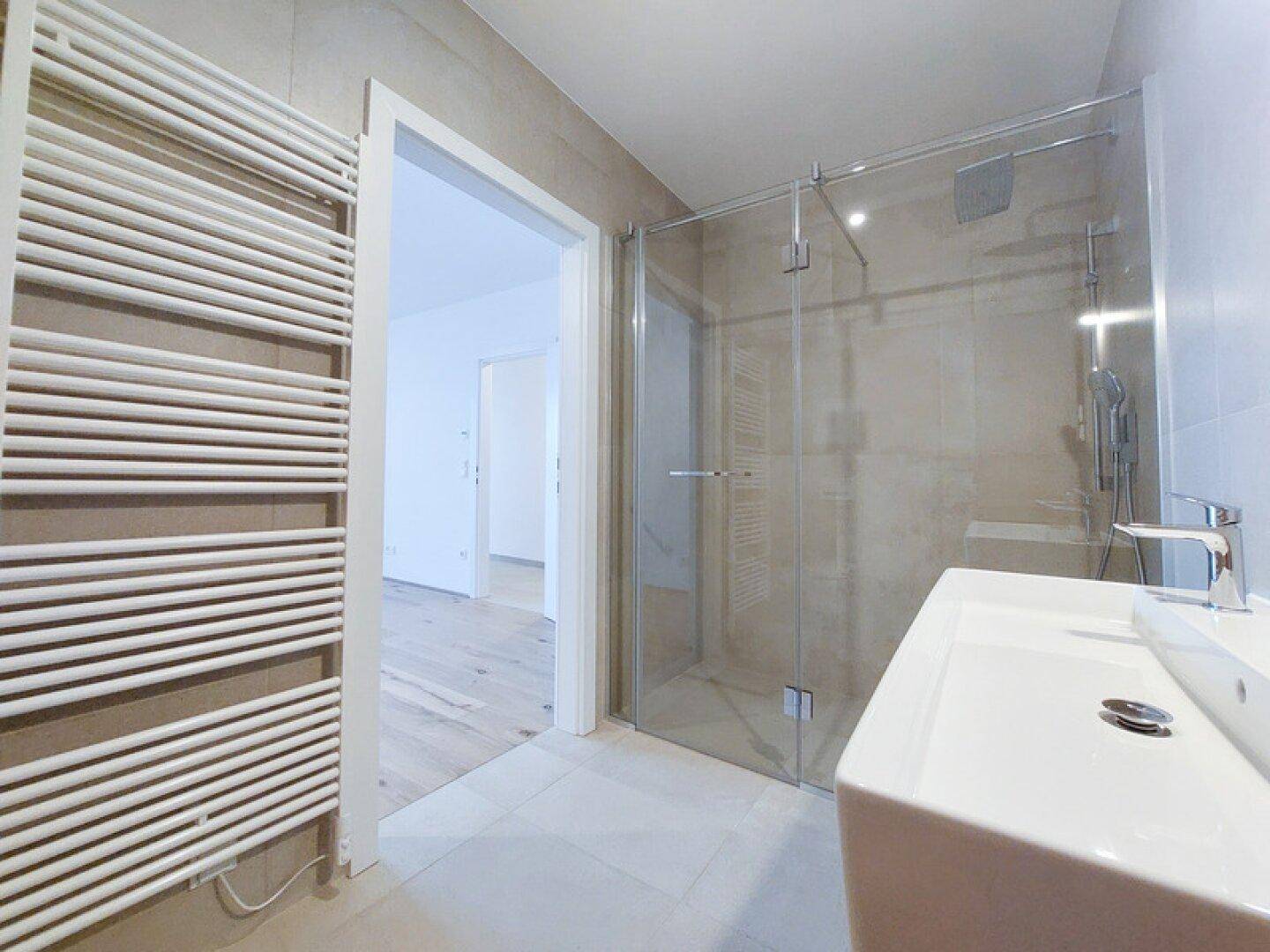 Modernes Badezimmer mit Duschkabine, Einzelwaschbecken und beheiztem Handtuchhalter.
