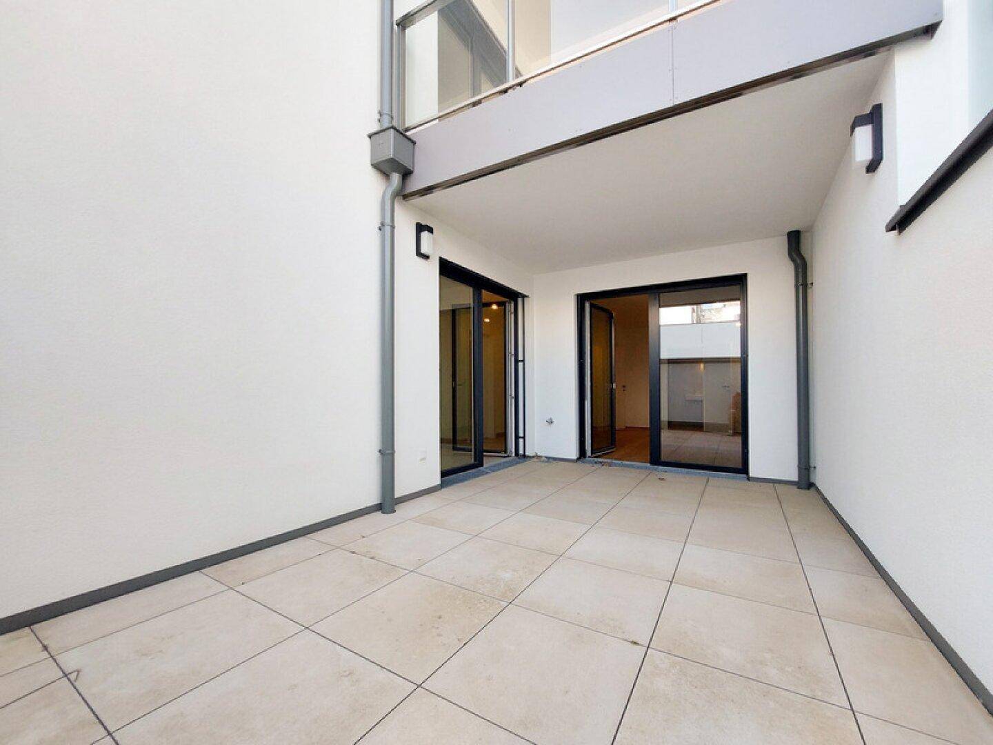 Geräumige Terrasse im Erdgeschoss mit Fliesenboden und direktem Zugang zum Innenbereich.