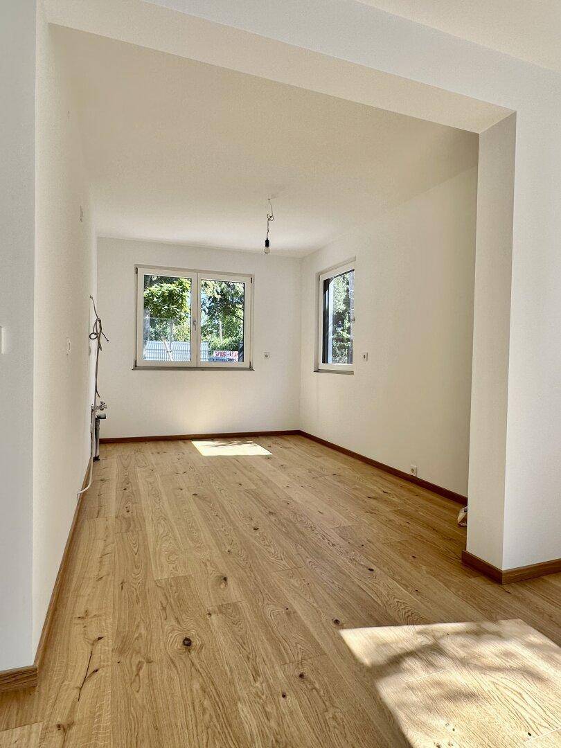 Heller, leerer Raum mit neuem Eichenparkettboden und weißen Wänden, bereit zur individuellen Gestaltung.
