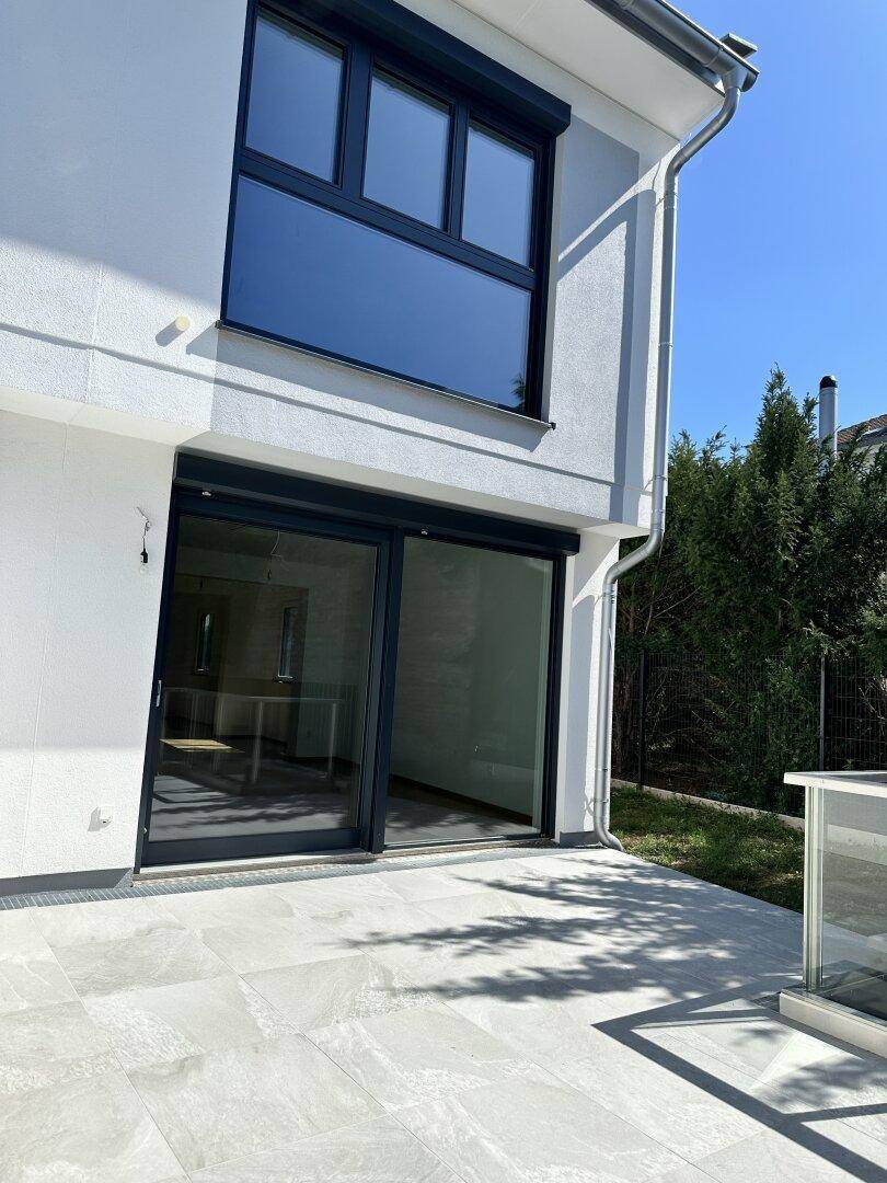 Moderne Terrasse mit großen Schiebetüren und Fliesenboden, ideal für entspannte Stunden im Freien.