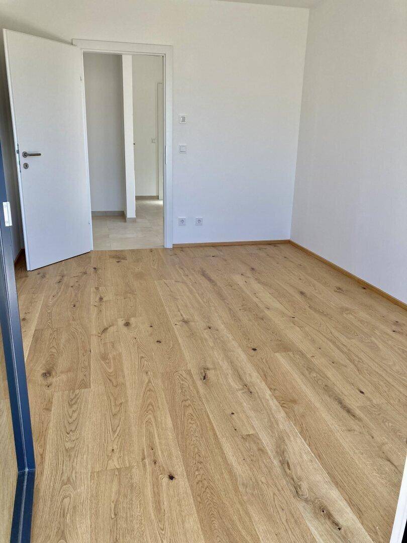 Freundliches Zimmer mit hellem Eichenparkettboden und weiß gestrichenen Wänden, ideal als Schlaf- oder Arbeitszimmer.