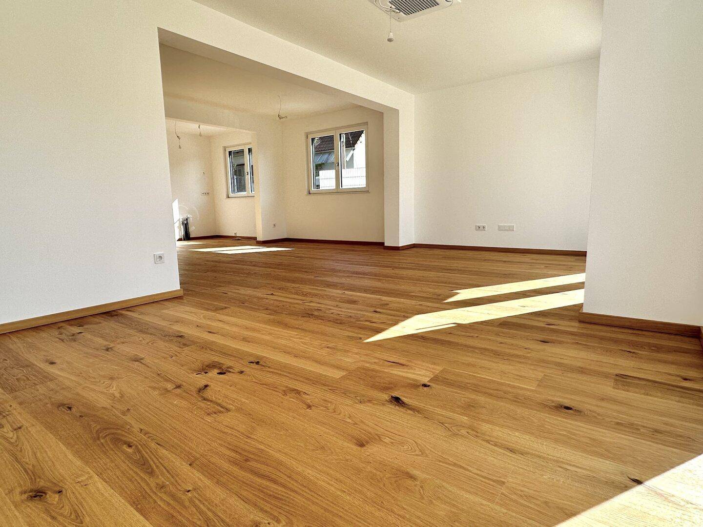 Helles, offenes Zimmer mit neuem Holzfußboden und weißen Wänden, ideal für Wohnbereiche.