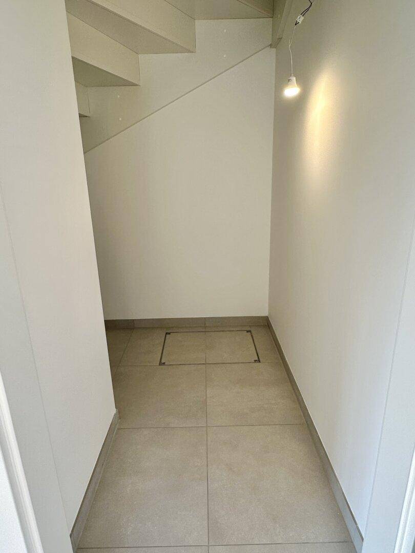 Kleiner Flurbereich unter der Treppe mit Fliesenboden und Zugang zu einem Stauraum.