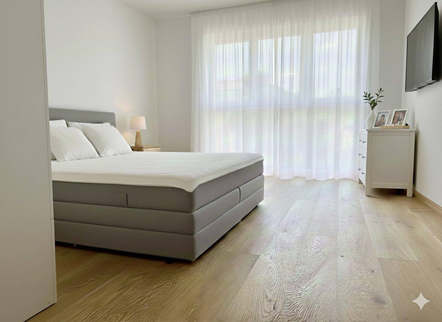 Helles Schlafzimmer mit großem Bett, Eichenparkett und bodentiefen Fenstern mit Vorhängen.