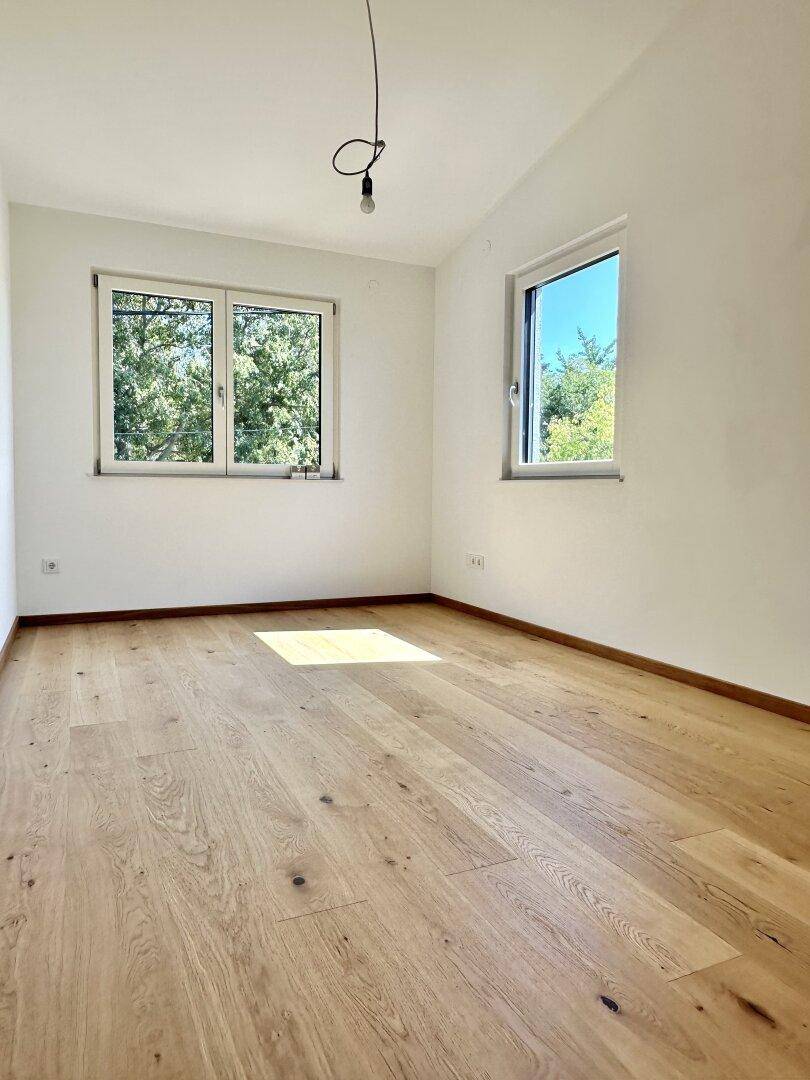 Leerer Raum mit hellem Eichenparkettboden und zwei Fenstern, ideal für individuelle Nutzung.