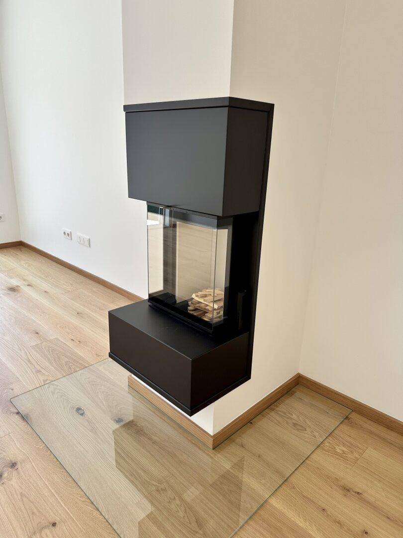 Moderner, schwarzer Kamin mit Glasfront und Eichenparkettboden, elegant in die Wand integriert.