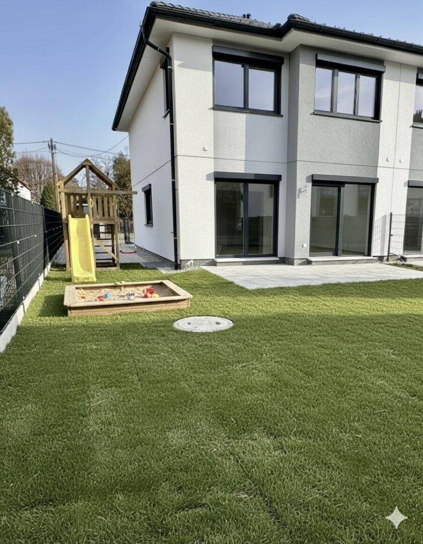 Moderner Gartenbereich mit Rasenfläche, Kinderspielplatz mit Rutsche und Sandkasten neben dem Haus.