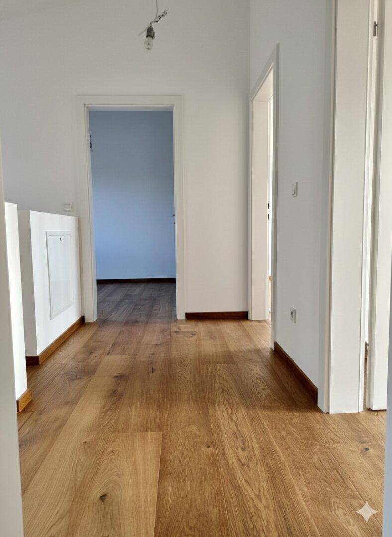Heller Flur mit Holzfußboden, der zu weiteren Zimmern im Haus führt.