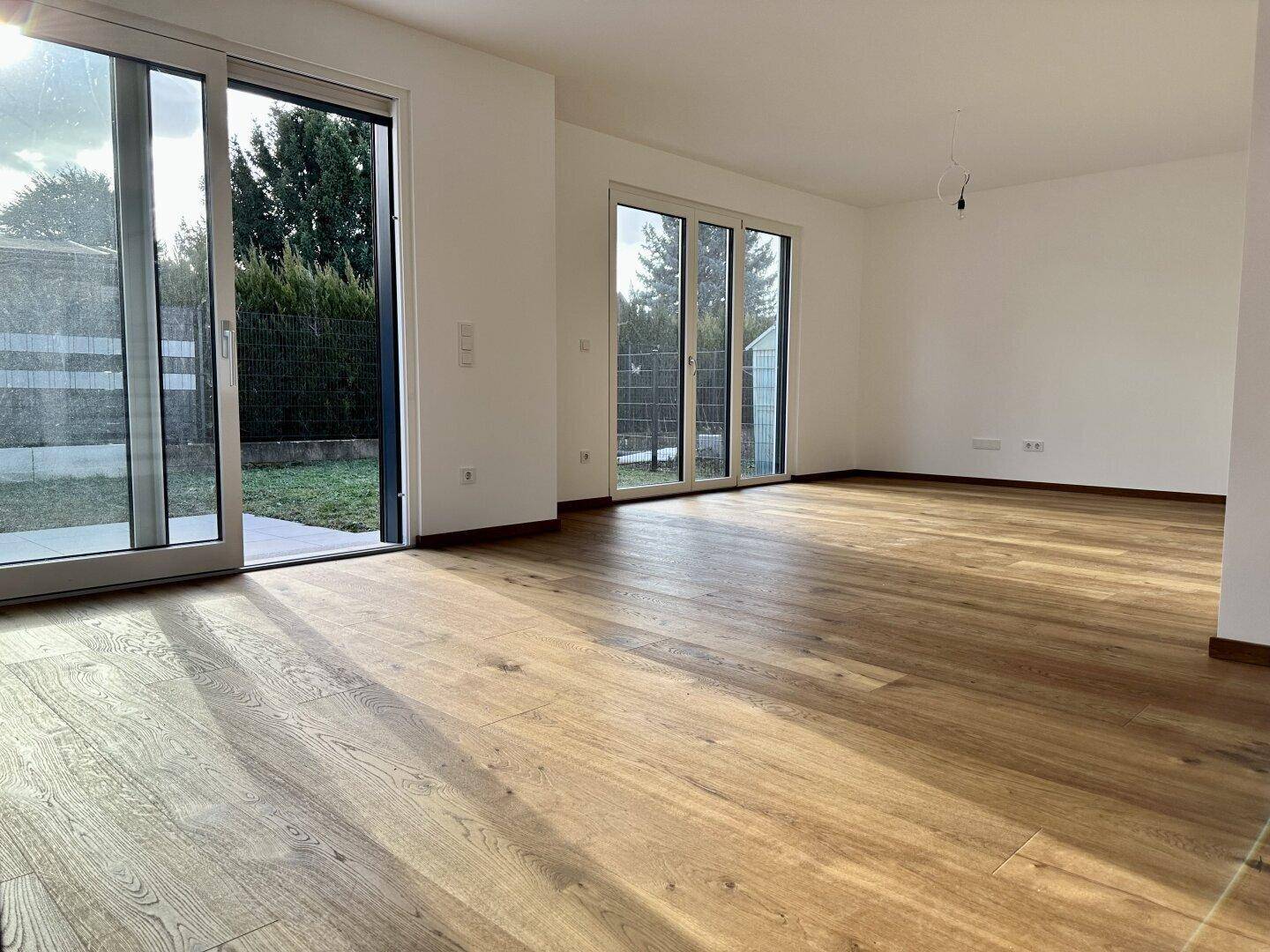 Geräumiges Wohnzimmer mit viel Tageslicht und direktem Zugang zum Garten.
