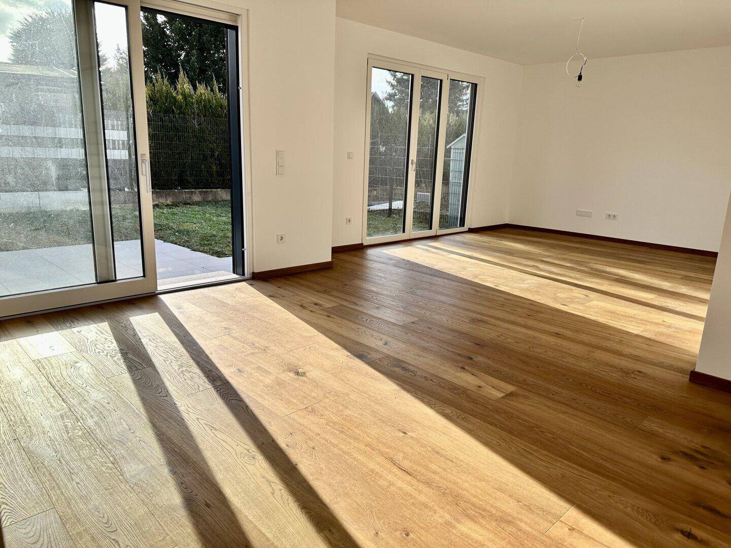 Helles Wohnzimmer mit großen Schiebetüren zum Garten und hochwertigem Holzfußboden.