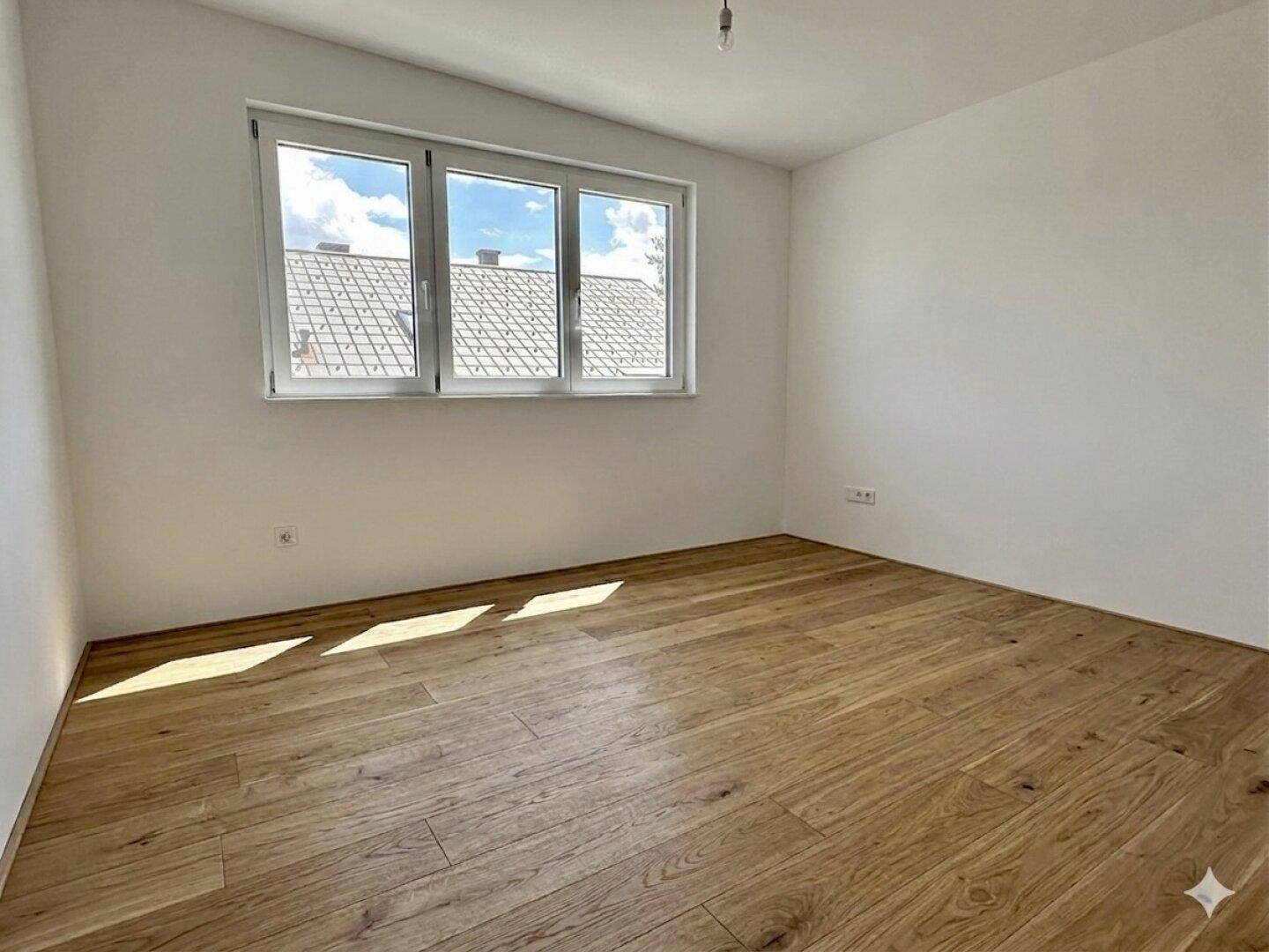 Lichtdurchflutetes Schlafzimmer mit Holzboden und Dachschräge, bietet einen schönen Ausblick und viel Helligkeit.