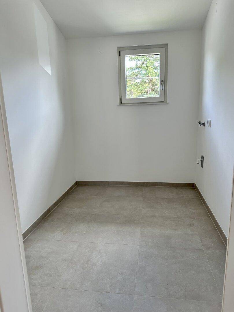 Kleiner Abstellraum mit Fliesenboden und Fenster, ideal für zusätzlichen Stauraum.