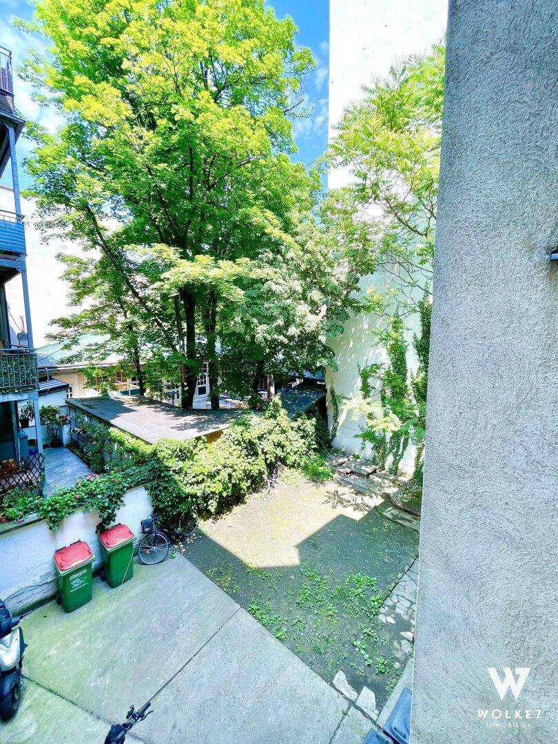 Blick von oben in den begrünten Innenhof mit hohen Bäumen und viel natürlichem Licht.