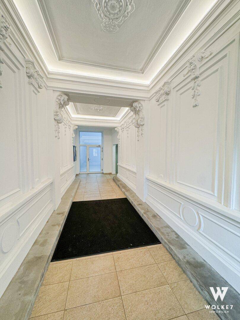 Prunkvoller Flur mit Stuckverzierungen an Wänden und Decke sowie eleganten Fliesen.