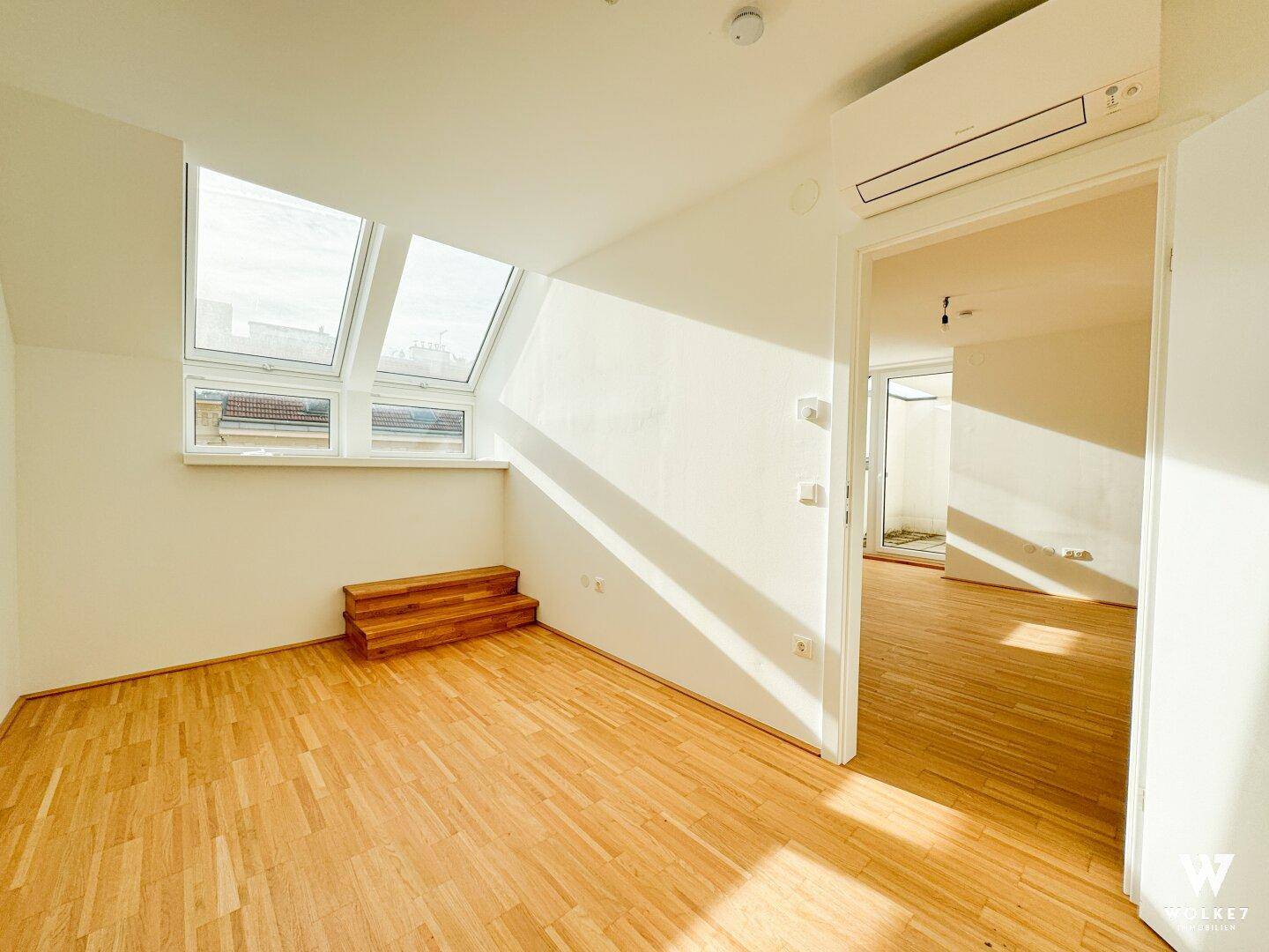 Helles Zimmer mit Holzboden, Dachfenstern und Klimaanlage, bereit zur individuellen Gestaltung.