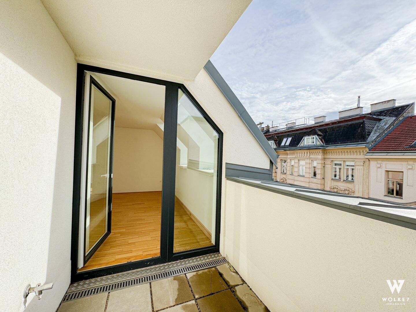 Kleiner Balkon mit Fliesenboden und Blick auf die umliegenden Dächer und Gebäude.