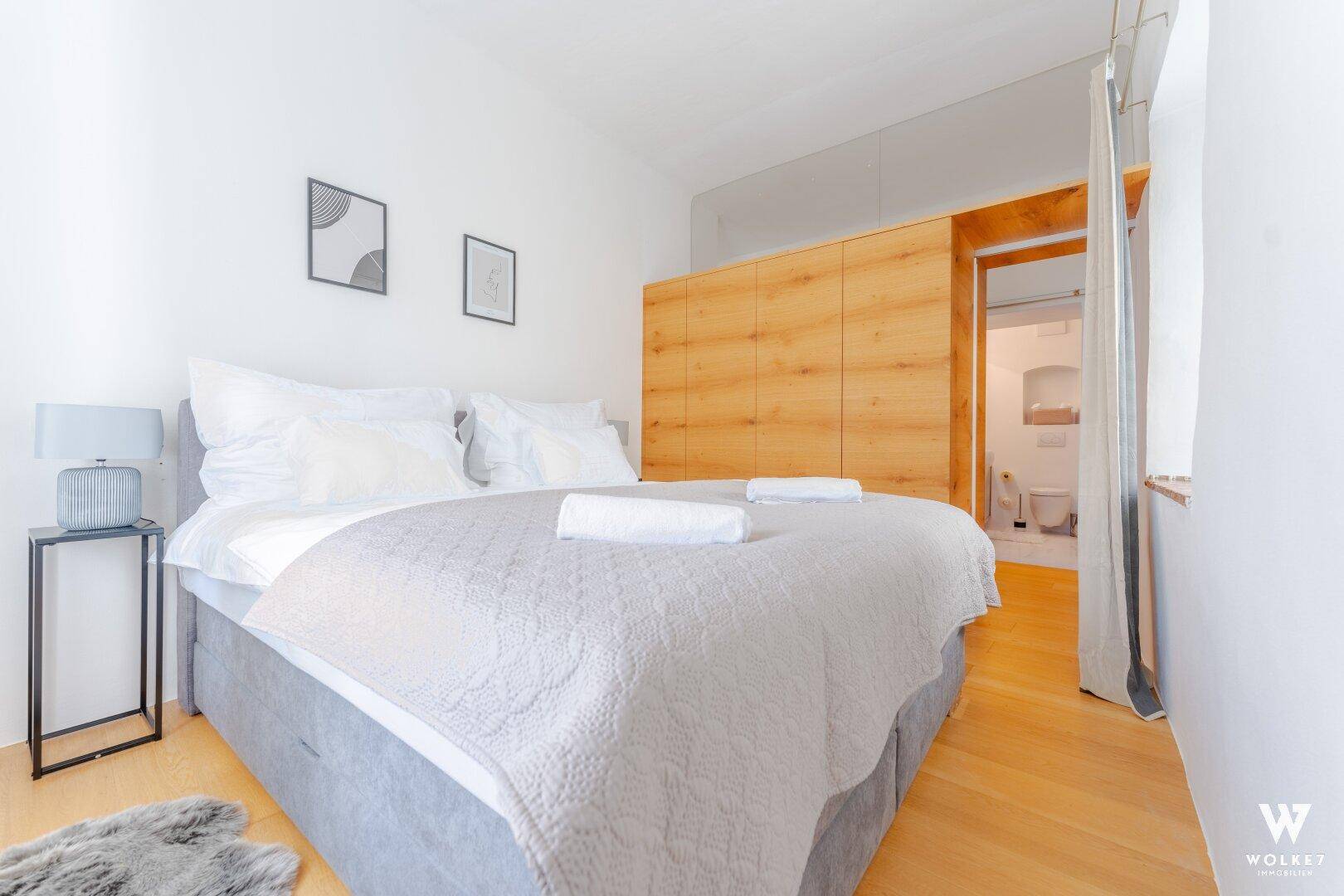 Gemütliches Schlafzimmer mit Doppelbett, Holzwänden und Zugang zu einem Badezimmer.