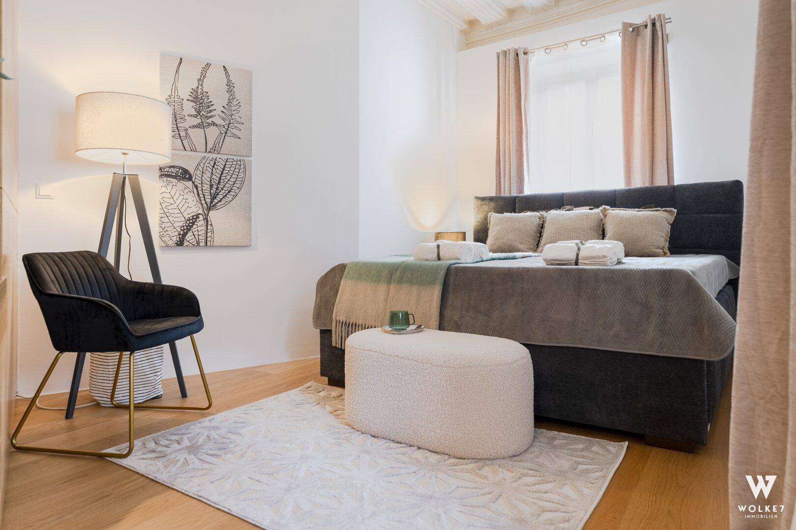 Gemütliches Schlafzimmer mit großem Bett, Holzboden und stilvoller Beleuchtung unter hohen Decken.