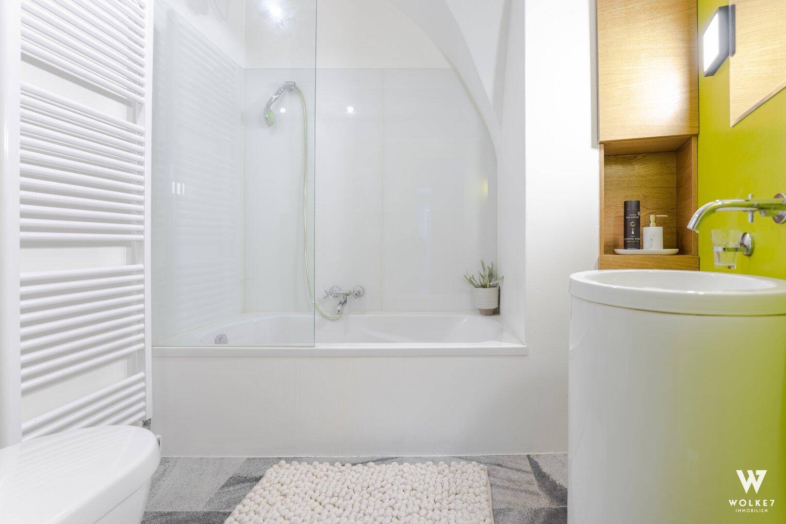 Helles Badezimmer mit Badewanne, Dusche und beheiztem Handtuchhalter in modernem Design.