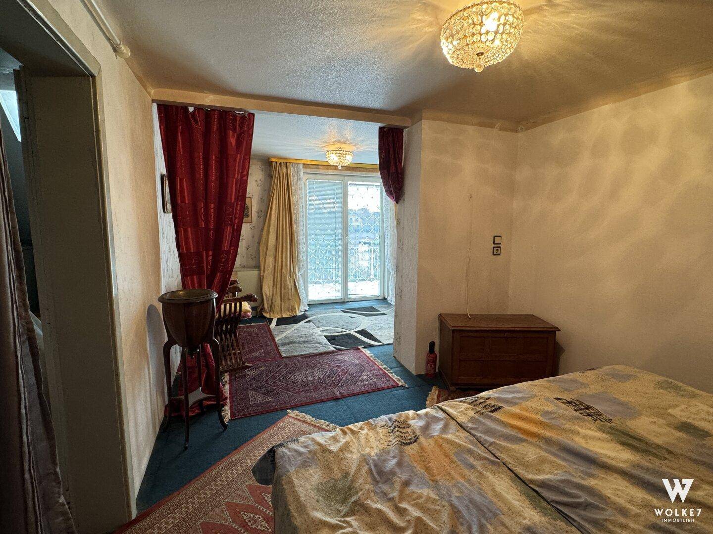 Schlafzimmer mit Teppichboden und einem Durchgang zu einem weiteren Raum.