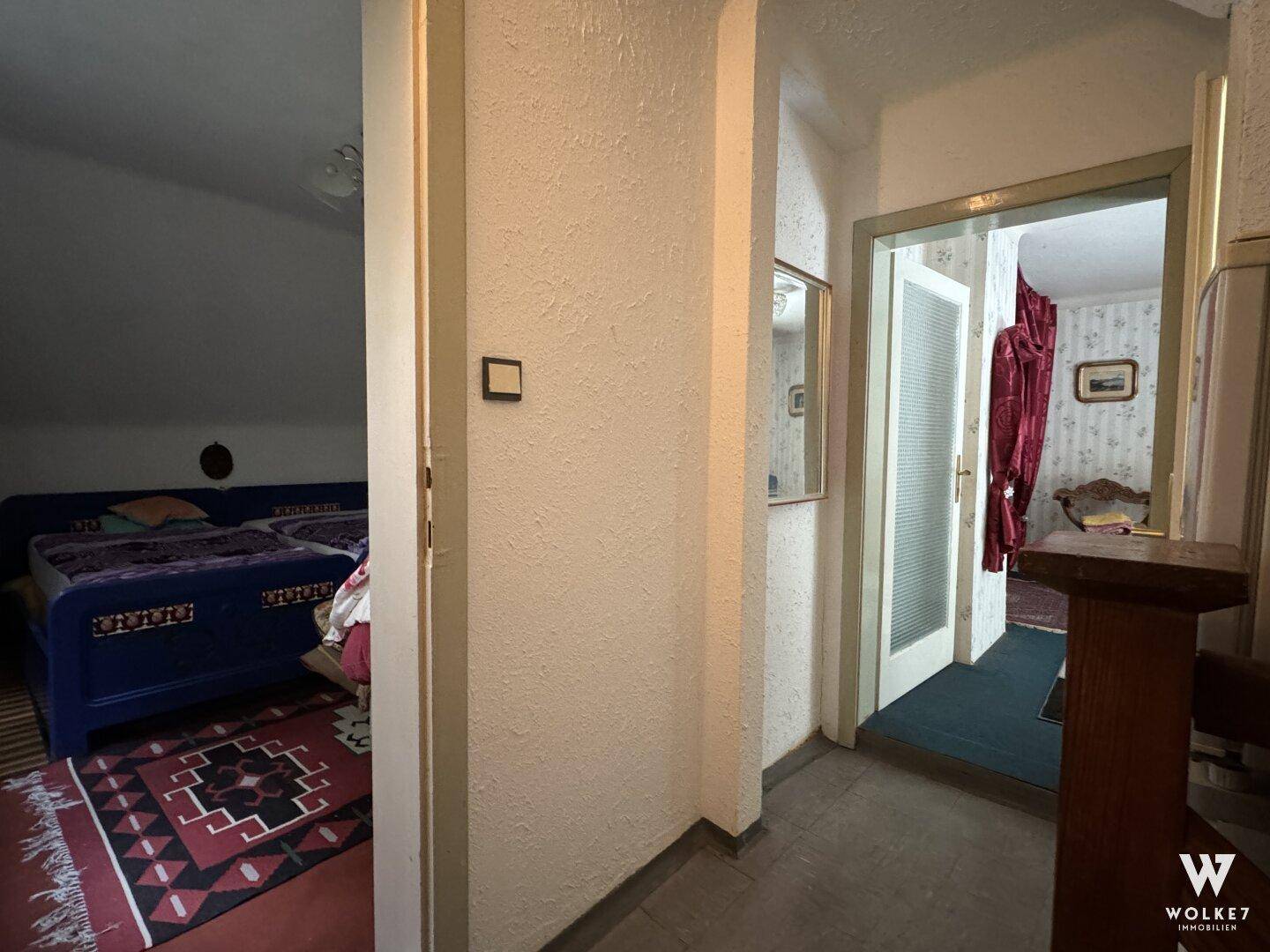 Flur mit Zugang zu einem Schlafzimmer, gekennzeichnet durch einen Teppichboden.