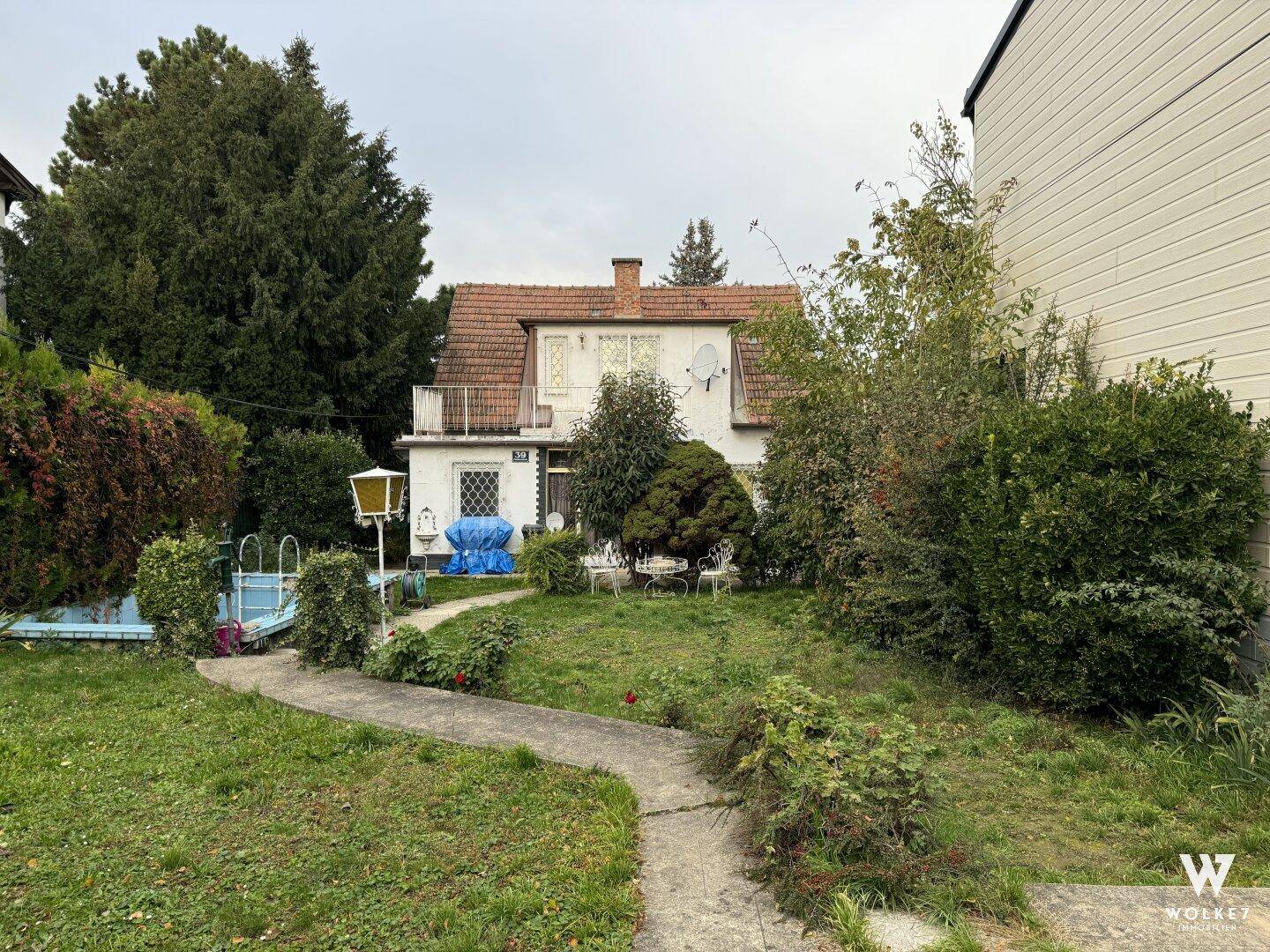 Blick auf das Haus vom Garten aus mit einem gewundenen Weg und üppiger Vegetation.