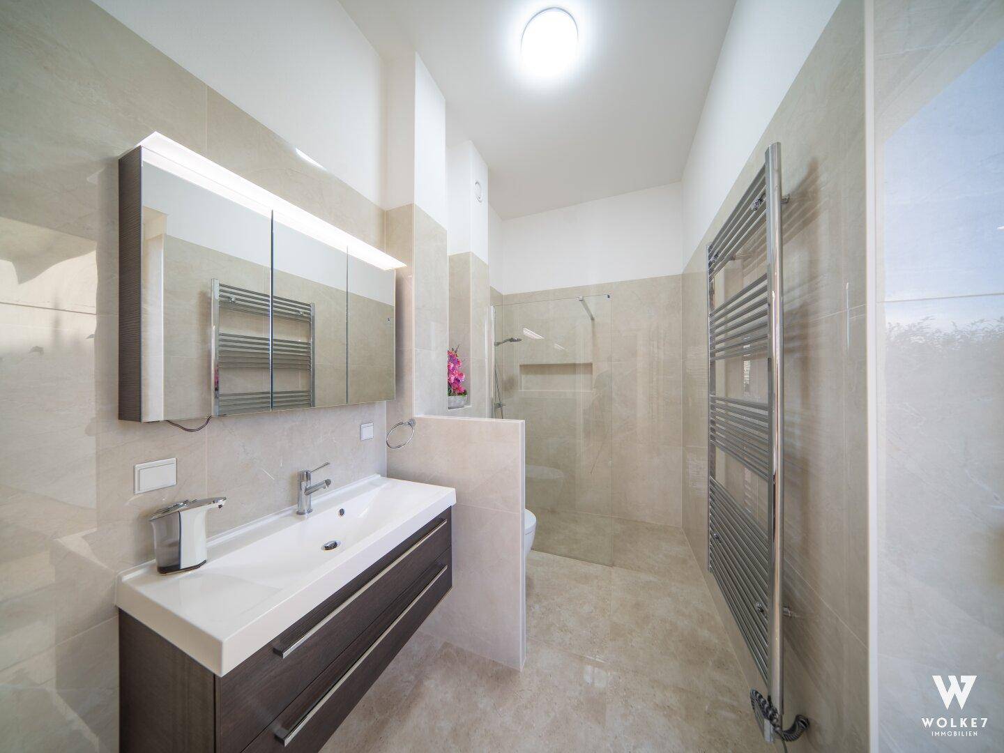 Modernes Badezimmer mit begehbarer Dusche, Einzelwaschbecken und beheiztem Handtuchheizkörper.
