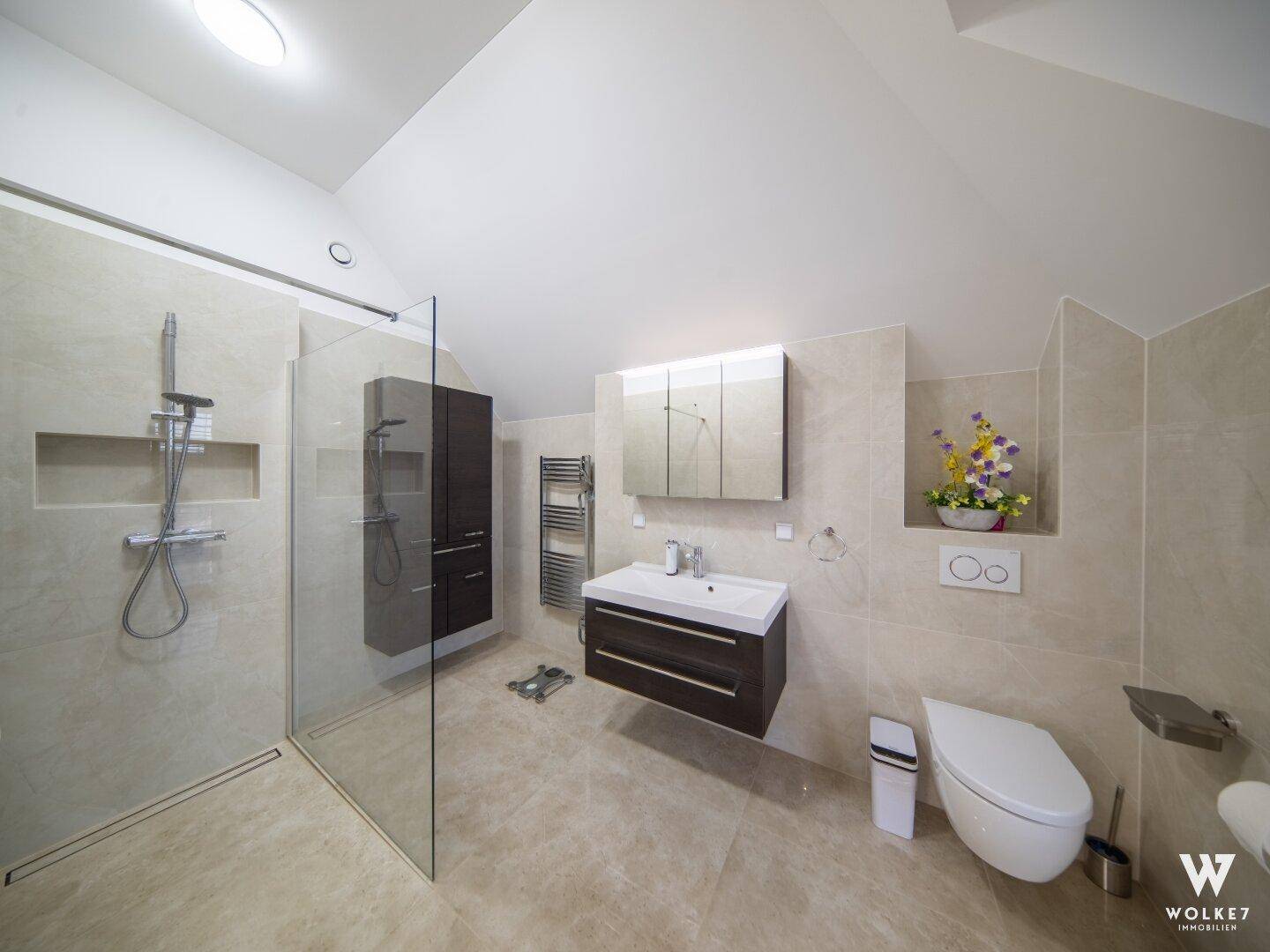 Modernes Badezimmer mit begehbarer Dusche, wandhängendem WC und beheiztem Handtuchheizkörper.
