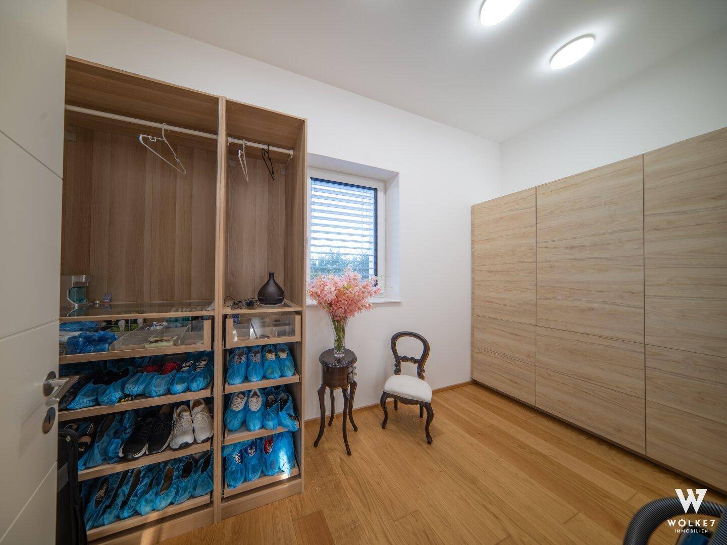 Geräumiges Ankleidezimmer mit Einbauschränken, Holzoberflächen und einem Fenster.