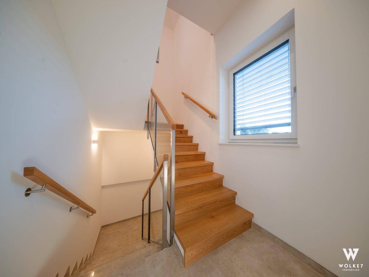 Moderne Holztreppe mit Glasgeländer, die die verschiedenen Etagen des Hauses verbindet.