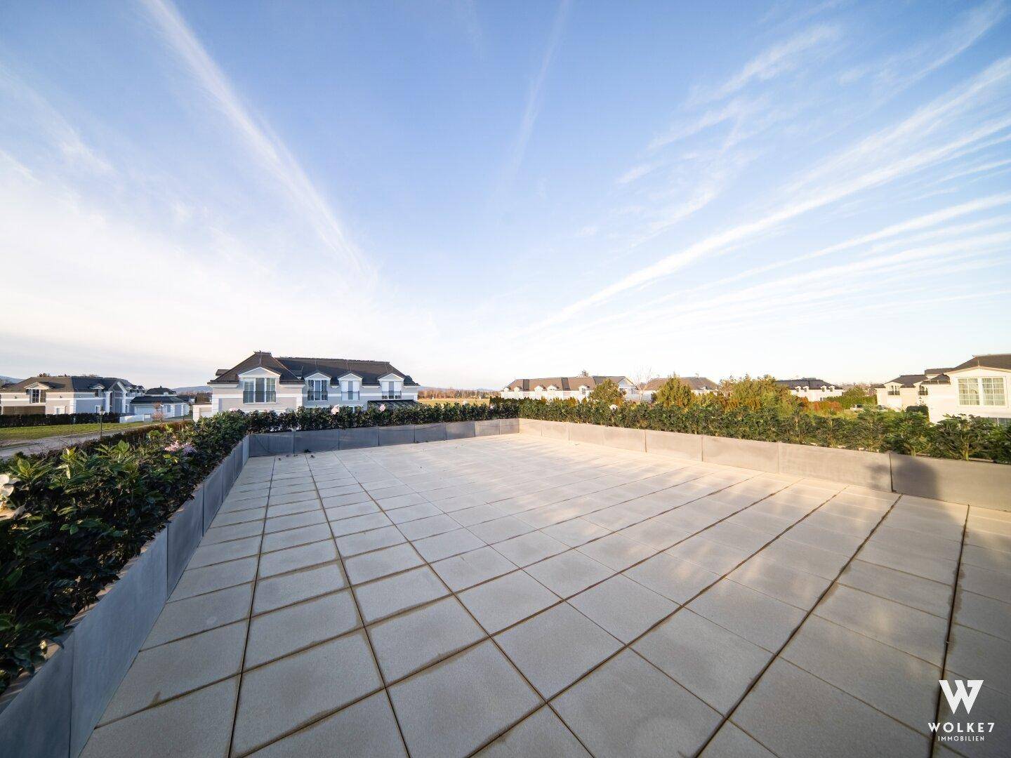Weitläufige Dachterrasse mit Fliesenboden und einem weiten Blick über die Umgebung.
