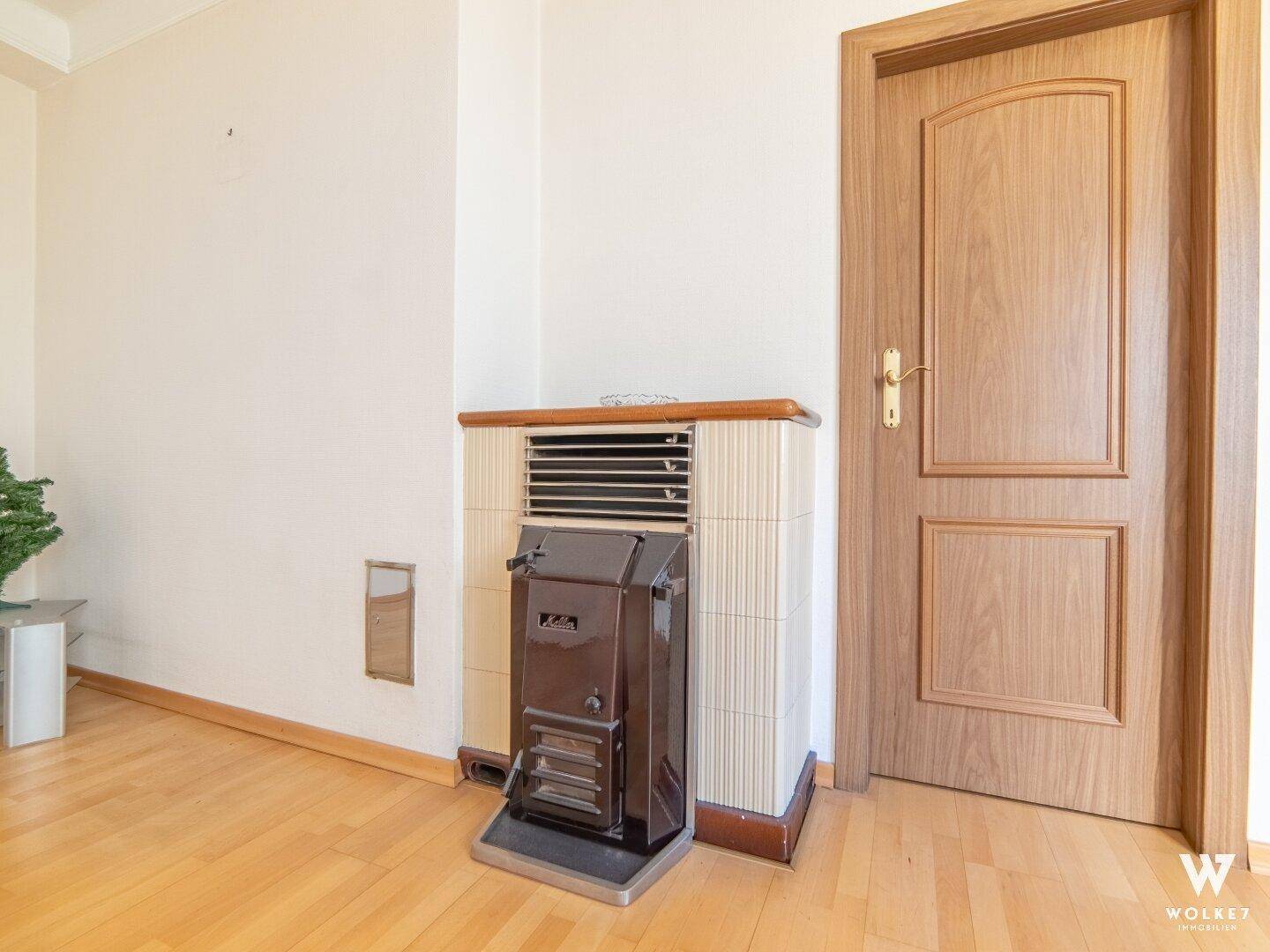 Detailansicht eines Gasofens im Wohnzimmer mit Holztür und Parkettboden, sorgt für Wärme.