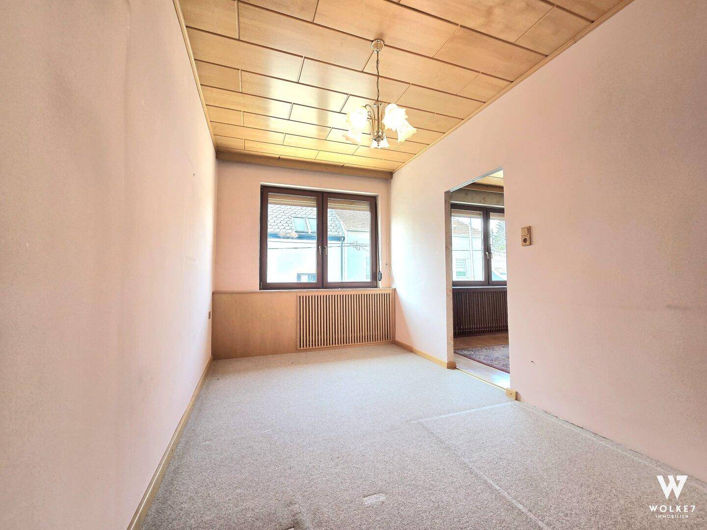 Schlafzimmer mit Teppichboden, Holzpaneeldecke und Fenster mit Blick nach draußen.