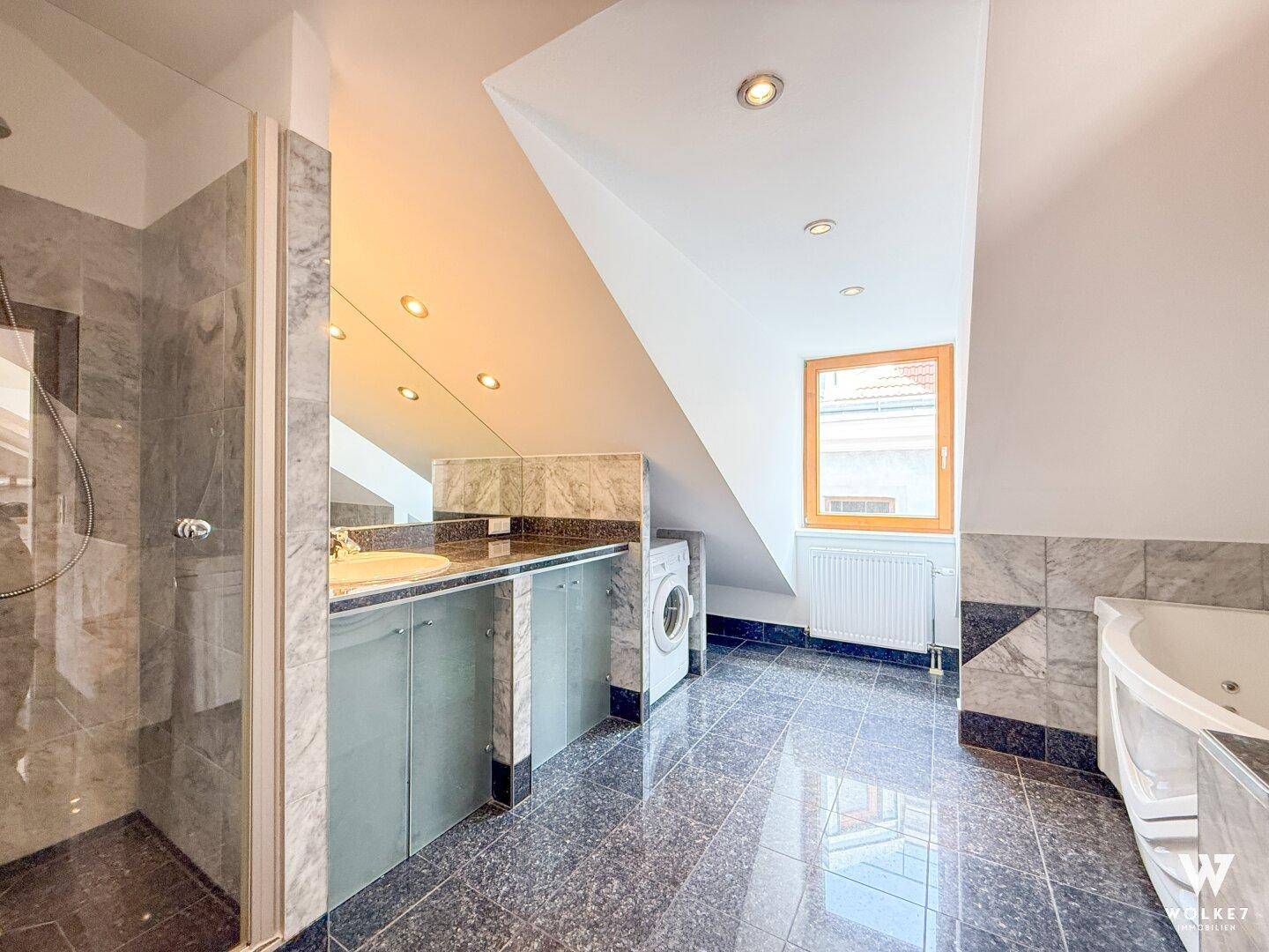Modernes Badezimmer im Dachgeschoss mit Marmorfliesen, Dusche, Badewanne und Waschmaschine.