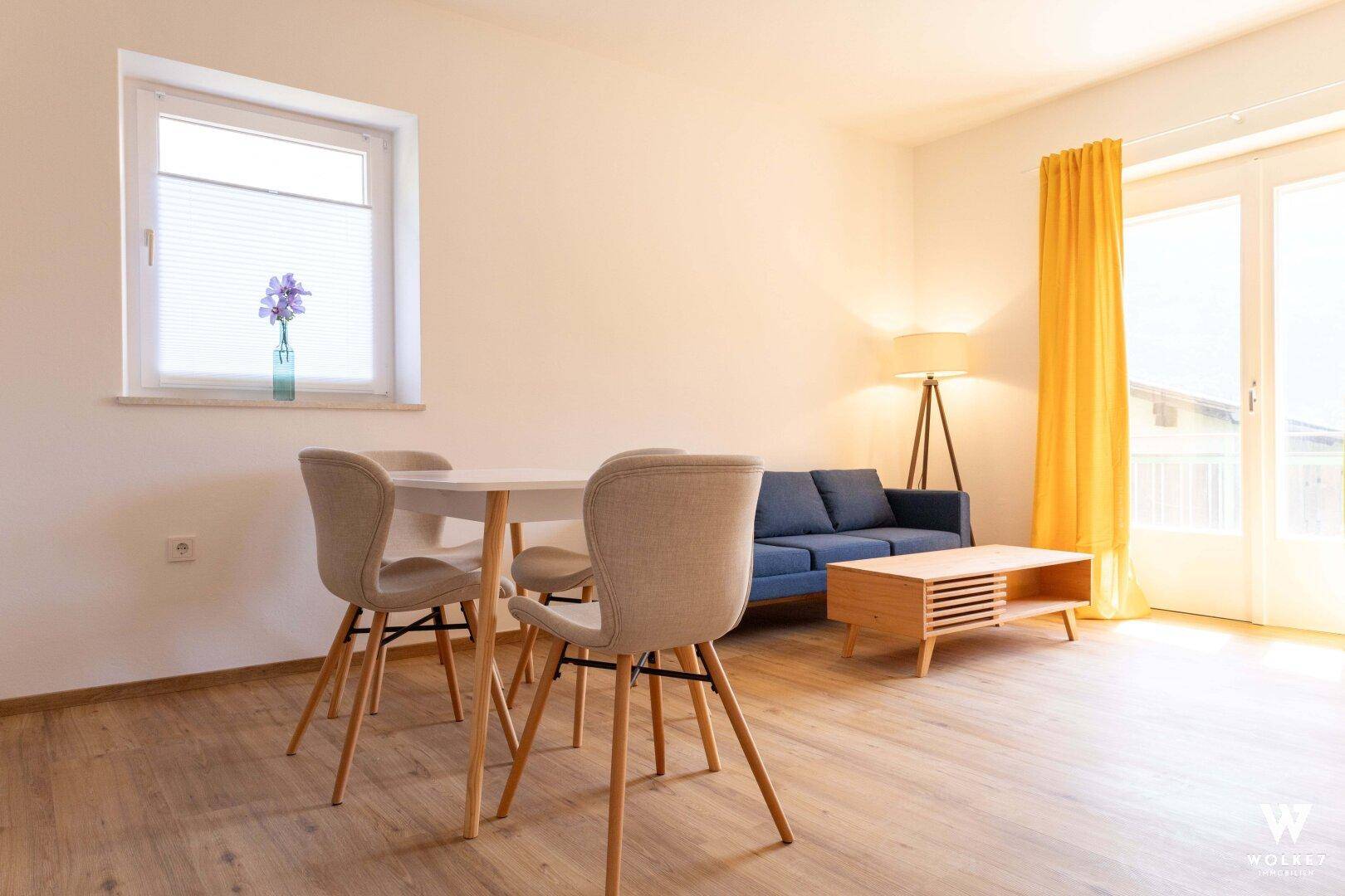 Heller Wohn- und Essbereich mit bequemer Couch, Esstisch und Zugang zu einem Außenbereich.