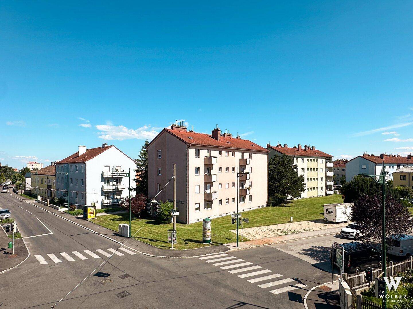 Weitläufiger Blick über eine ruhige Wohnstraße mit mehrstöckigen Apartmentgebäuden und Grünflächen.