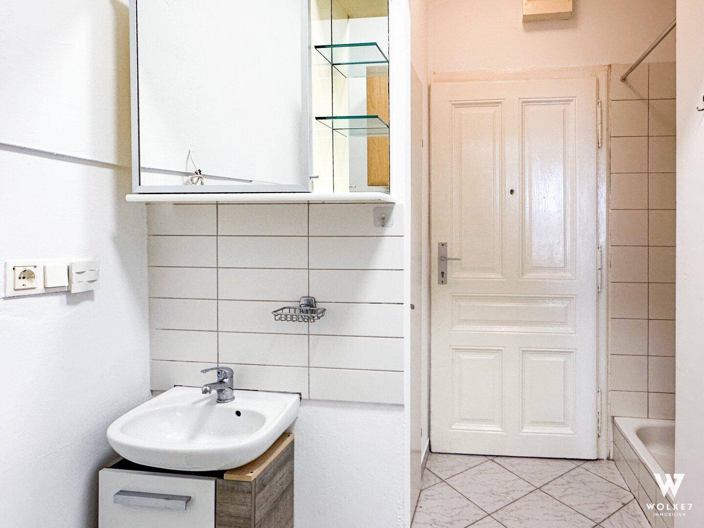 Kleines Badezimmer mit Waschbecken, Spiegelschrank und einer Badewanne, funktional eingerichtet.