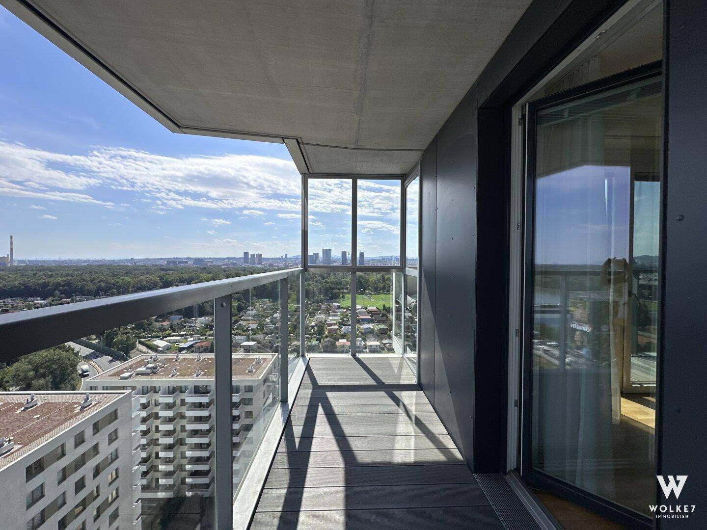 Moderner Balkon mit Glasgeländer und weitem Panoramablick über Stadt und Fluss.