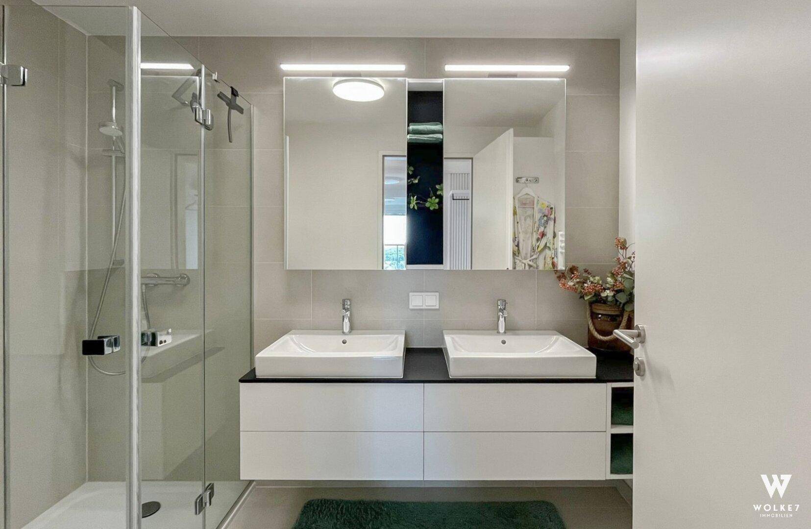 Modernes Badezimmer mit Doppelwaschbecken, Spiegelschränken und begehbarer Dusche.