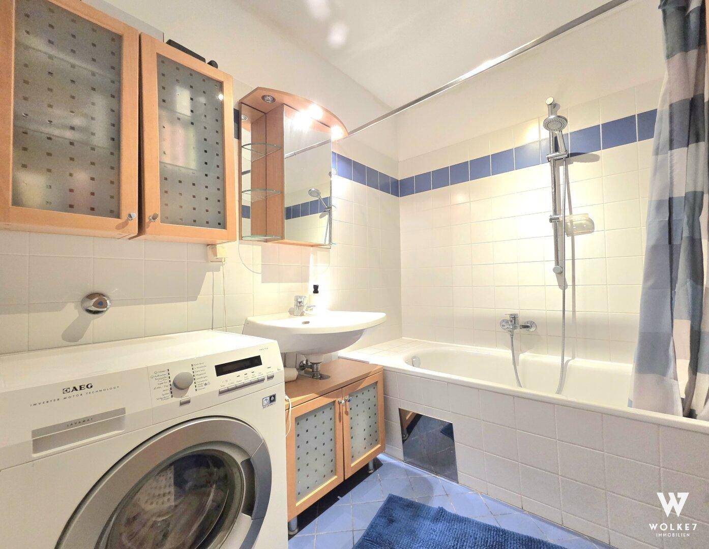 Badezimmer mit Badewanne, Waschbecken und integrierter Waschmaschine.