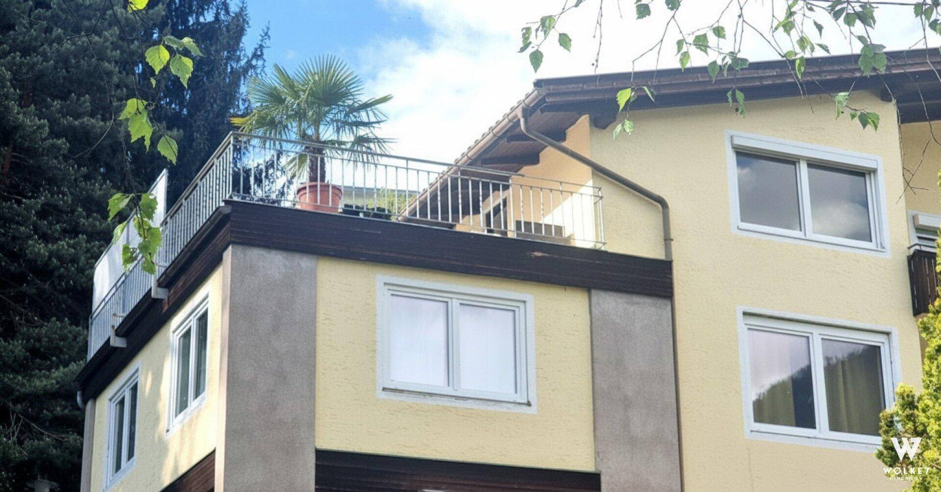 Gebäude mit einer zugänglichen Dachterrasse, ausgestattet mit einem Geländer und einer Palme.