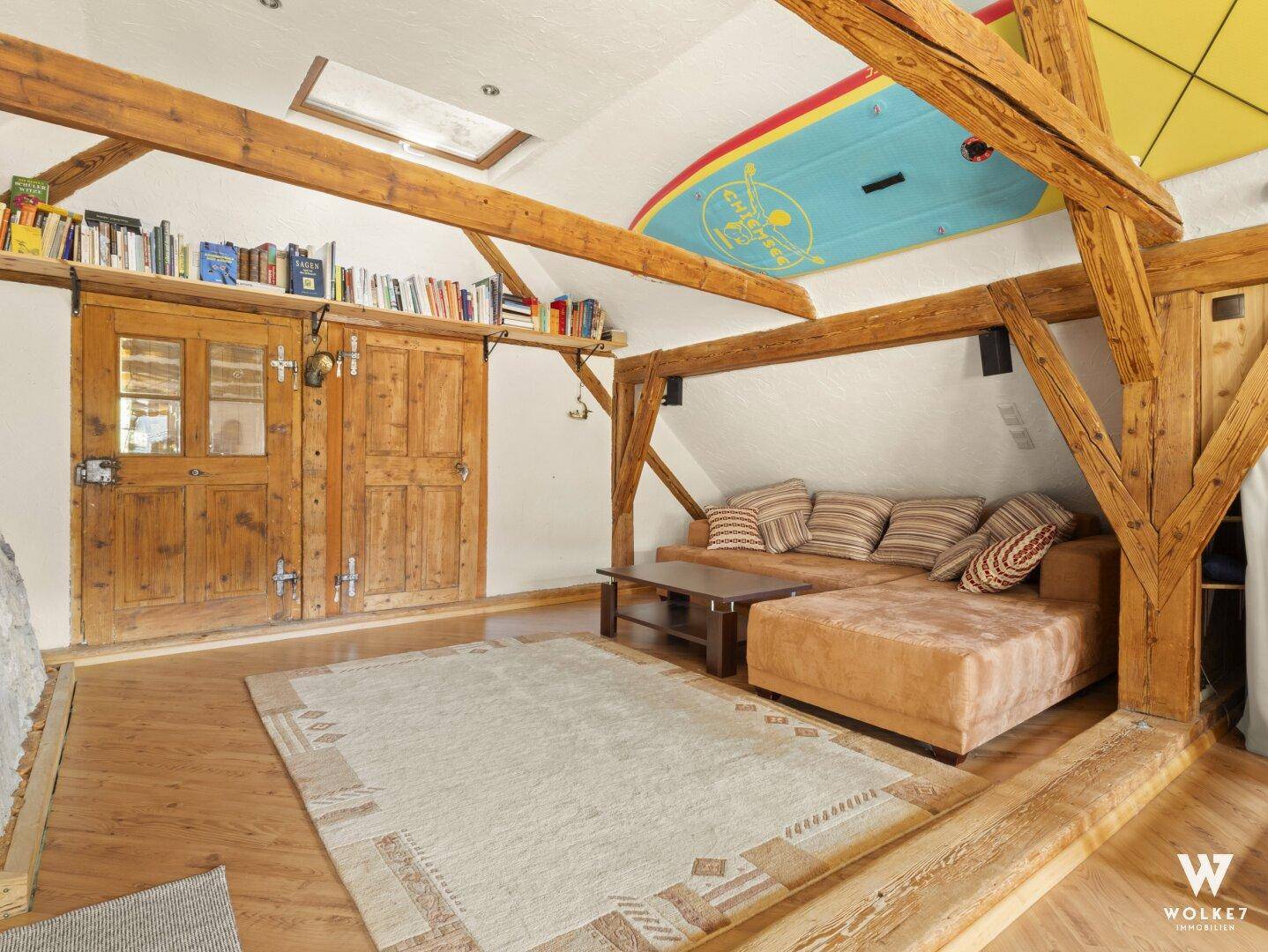 Heller Wohnbereich im Dachgeschoss mit Holzbalken, Schrägdach und Holzboden.