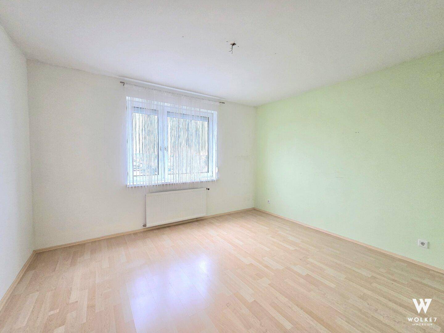 Geräumiges Zimmer mit hellem Parkettboden und Fenster, ideal als Schlaf- oder Kinderzimmer.