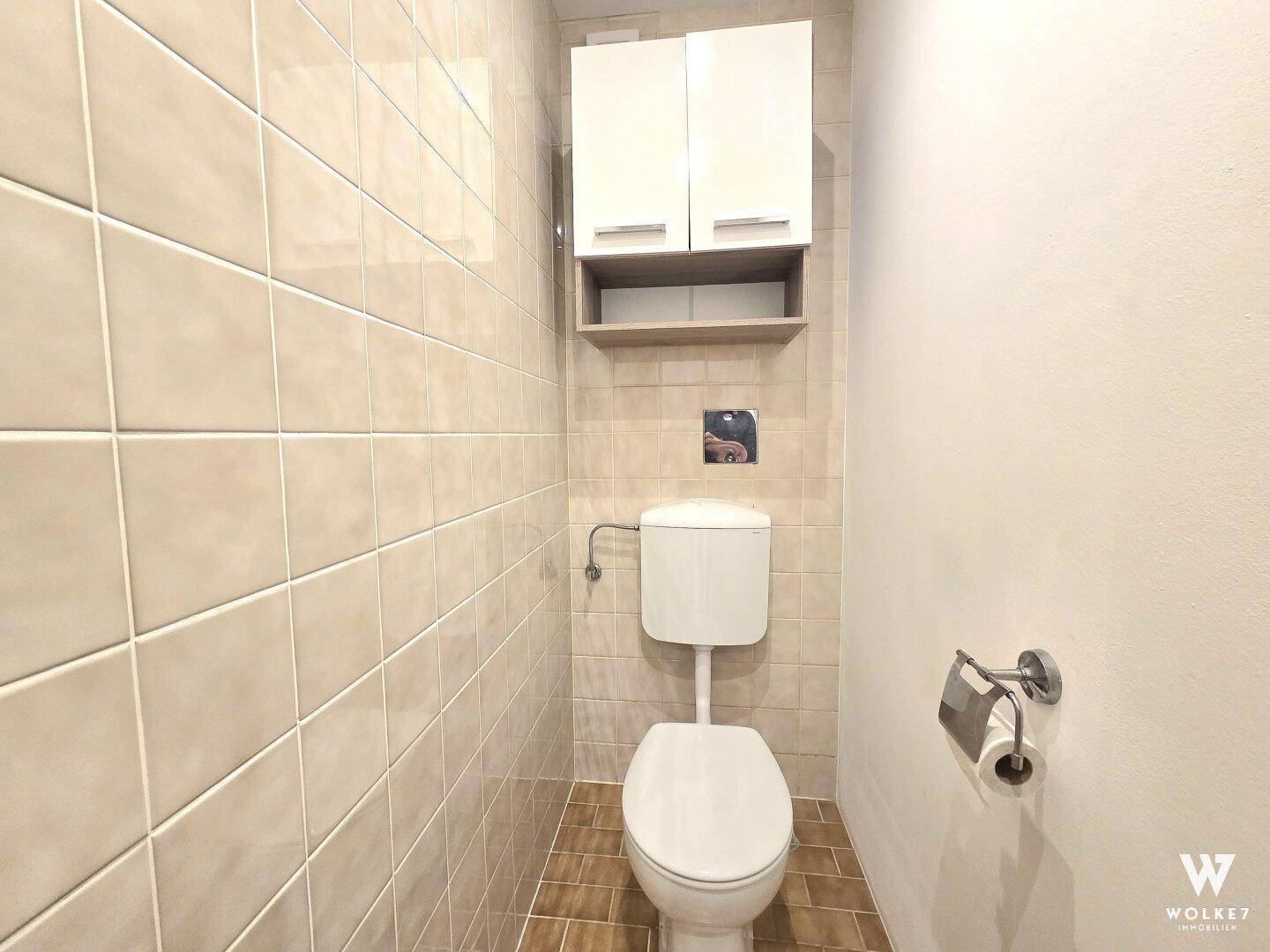 Separates Gäste-WC mit Wand-WC und hellen Fliesen, praktisch und funktional.