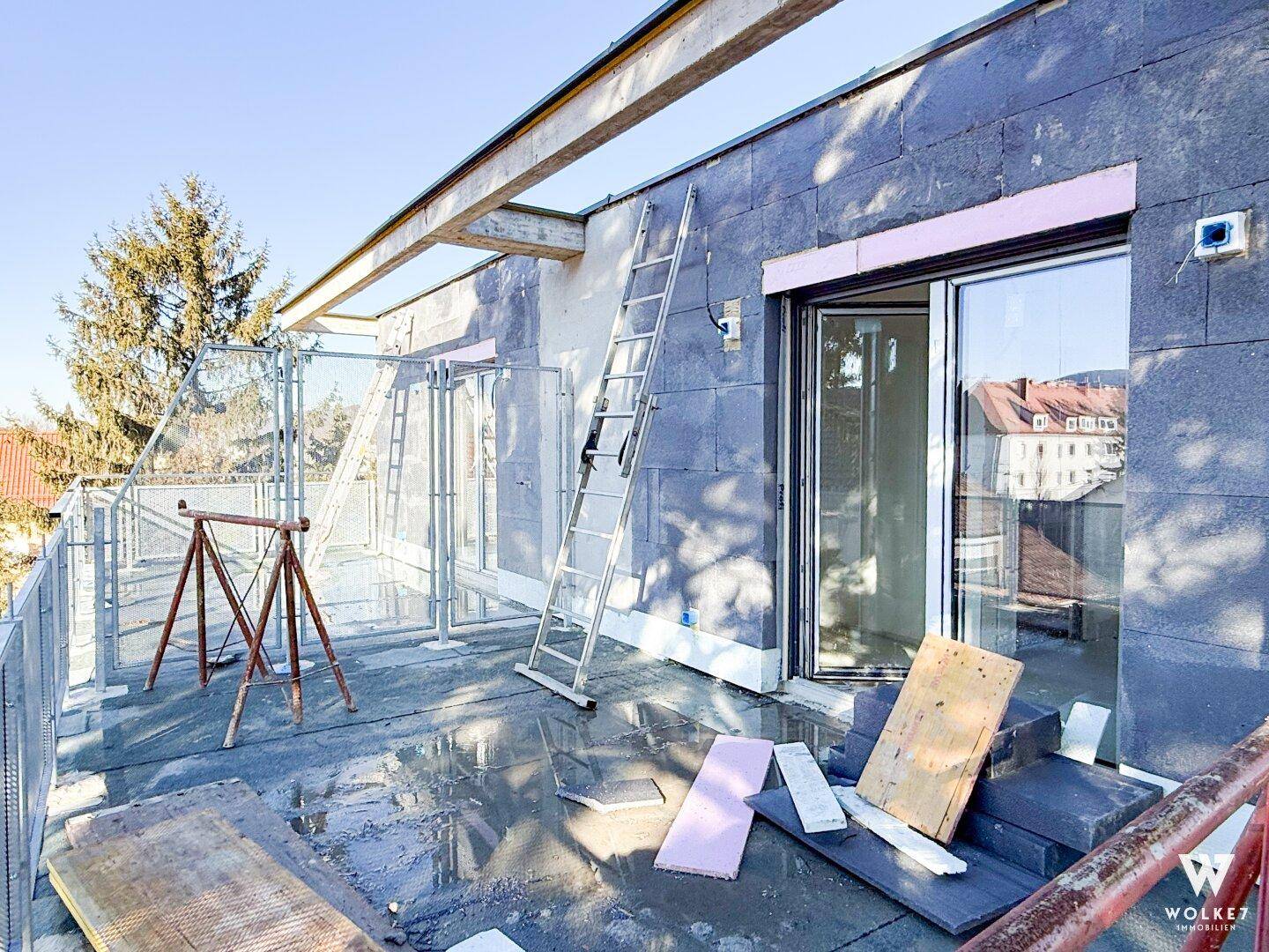 Dachterrasse im Bauzustand mit Baumaterialien und Blick auf die Umgebung.